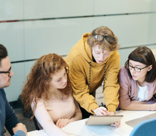 vier junge Menschen blicken gemeinsam auf ein Tablet