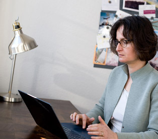 Rabea Wienholt sitzt an einem Schreibtisch und arbeitet am Laptop